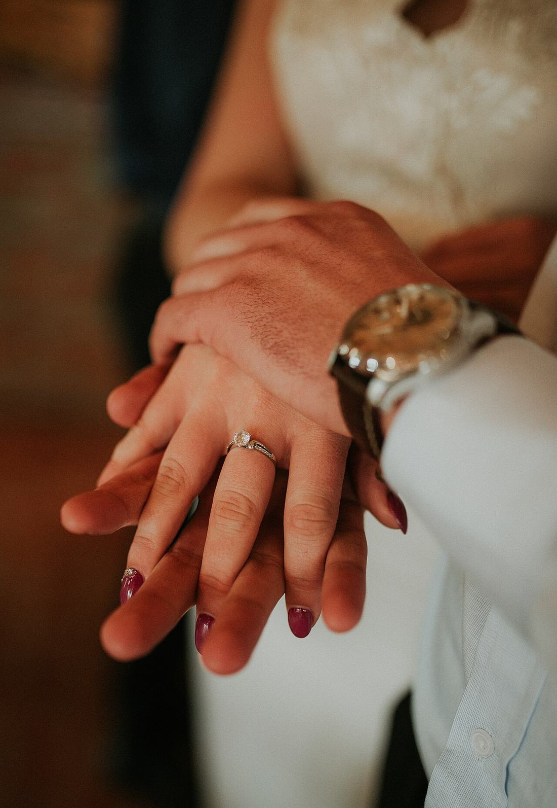 Couple holds hands showing wedding rings in a warm setting during a celebration